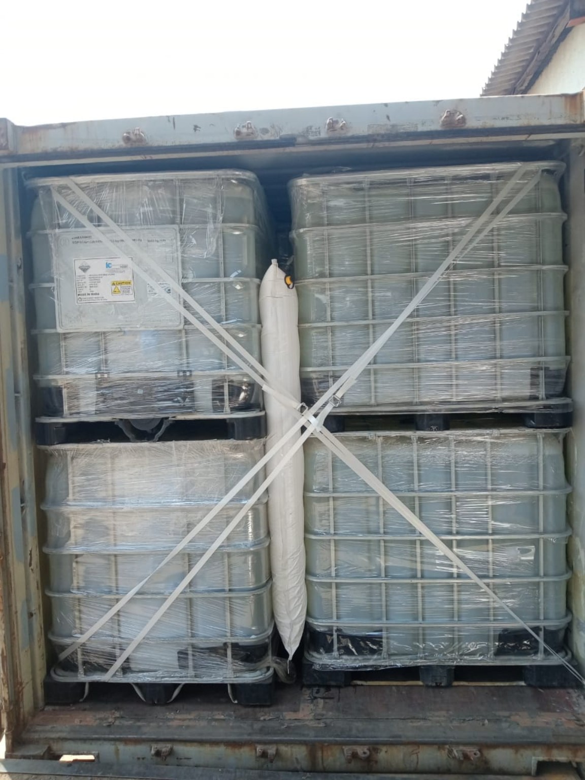 Four wrapped liquid containers secured with straps inside a shipping container